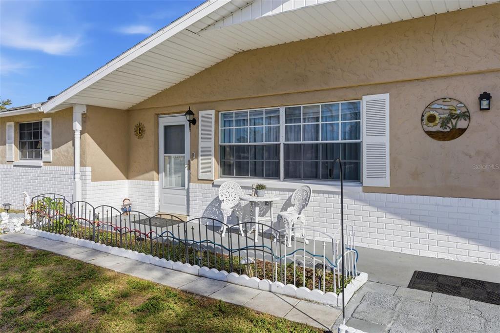 The exterior of a house features a white brick base, tan stucco walls, and a porch — 4904 ELMWOOD STREET, NEW PORT RICHEY, FL
