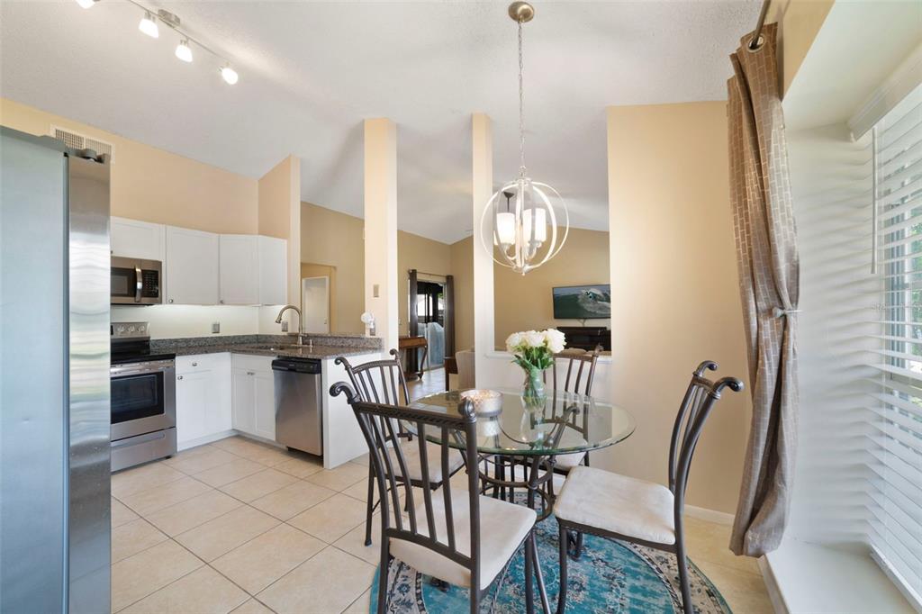 A kitchen with white cabinets and stainless steel appliances opens to a dining area — 13953 FOX MEADOW DRIVE, ORLANDO, FL