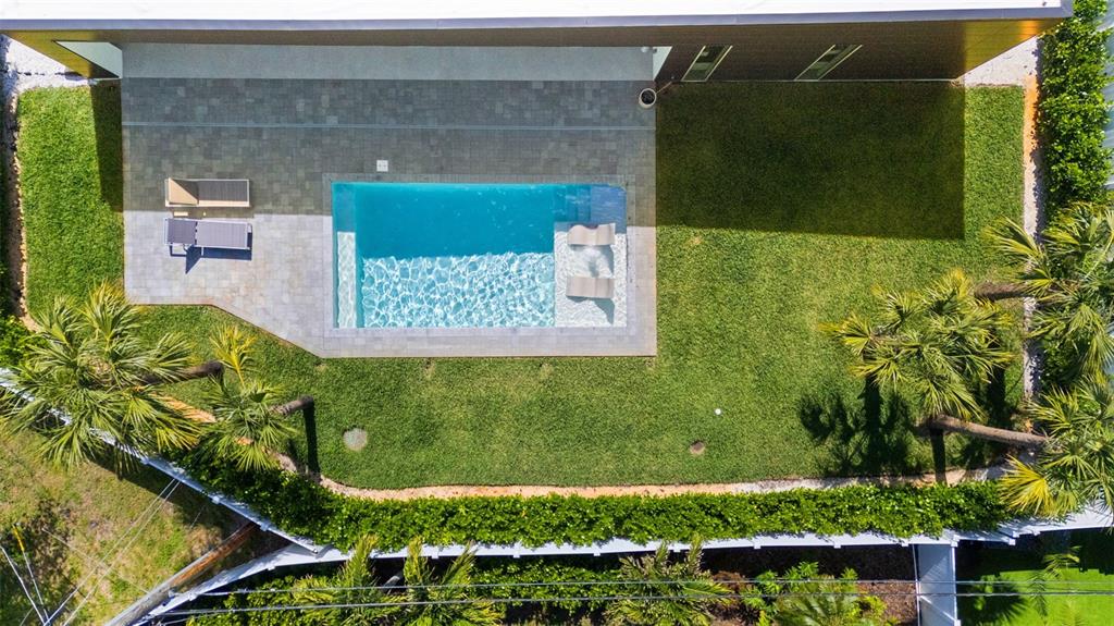 An aerial view shows a rectangular swimming pool with a tanning ledge in a backyard — 1304 INDIAN ROCKS ROAD, BELLEAIR, FL