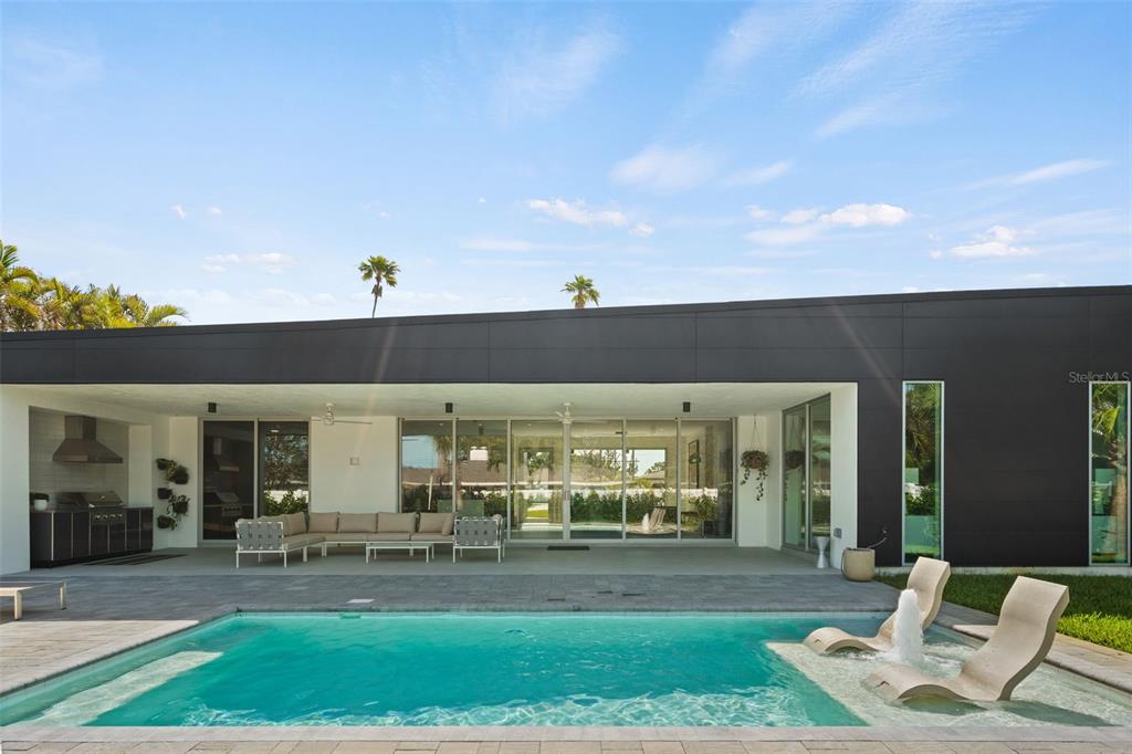 A modern home exterior features a covered patio, outdoor kitchen, and a swimming pool — 1304 INDIAN ROCKS ROAD, BELLEAIR, FL