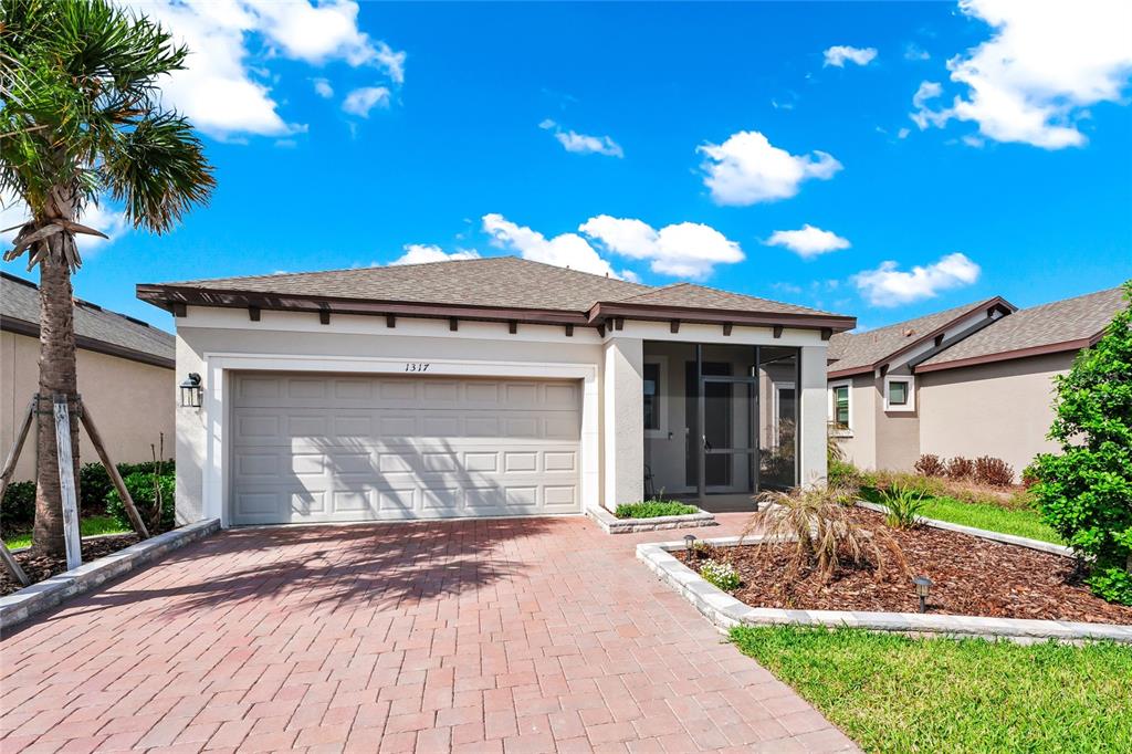 A single-story house with a brick paver driveway, two-car garage, and a screened front entryway — 1317 LOMBARDI COURT, KISSIMMEE, FL