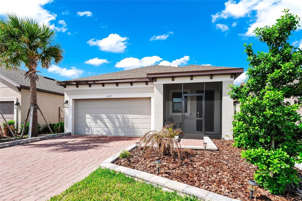 A single-story house with a brick driveway, a two-car garage, and a screened front entryway — 1317 LOMBARDI COURT, KISSIMMEE, FL