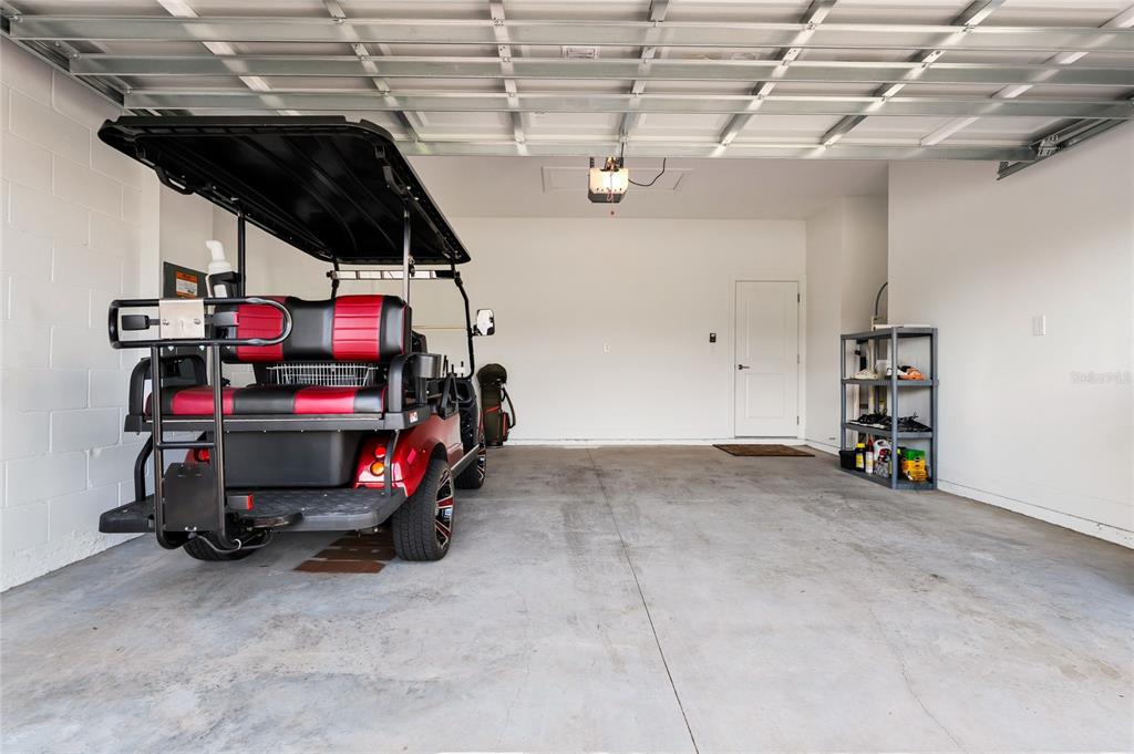 A garage with a concrete floor, a golf cart, and a storage shelf — 1317 LOMBARDI COURT, KISSIMMEE, FL