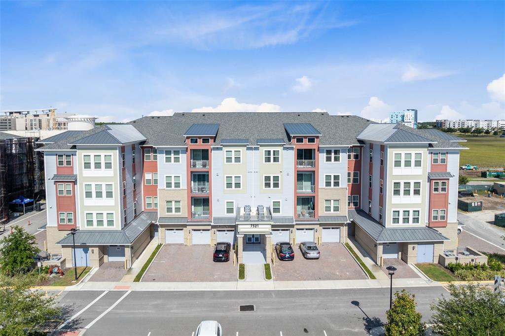 An exterior view of a multi-story apartment building with a parking area in front — 7521 LAUREATE BOULEVARD UNIT 5307, ORLANDO, FL