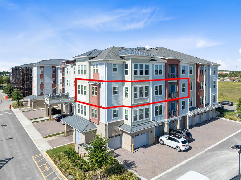 An exterior view of a multi-story apartment building with a red outline highlighting a unit — 7521 LAUREATE BOULEVARD UNIT 5307, ORLANDO, FL