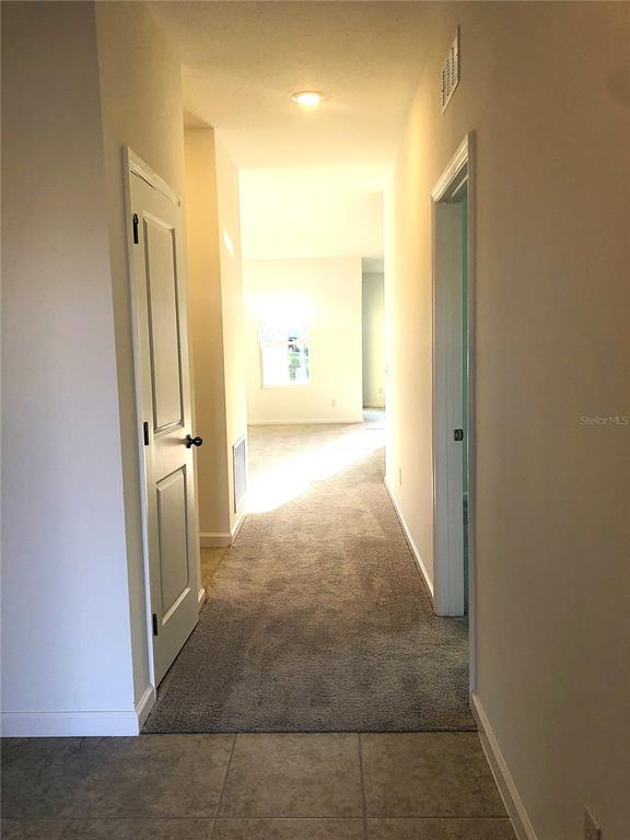 A hallway with carpeted flooring leads toward a bright room with a window — 1314 DALKEITH CV, SANFORD, FL