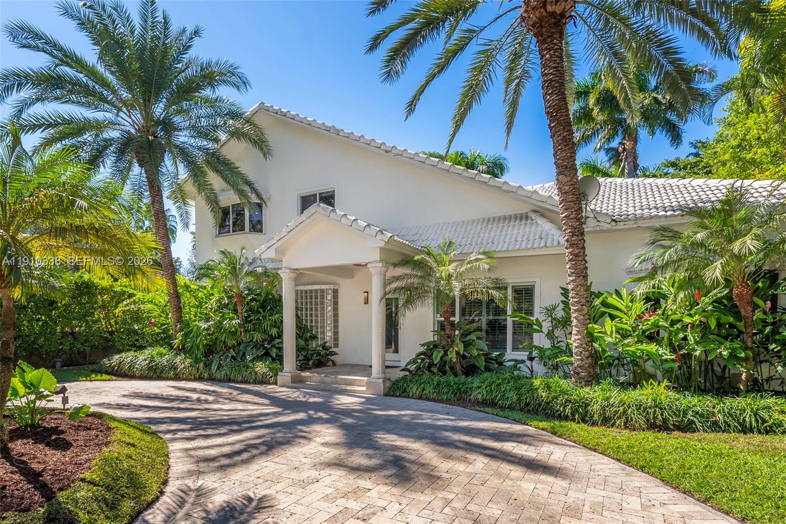 A white two-story house with a tiled roof and a paved driveway surrounded by palm trees — 6300 Allison Rd, Miami Beach FL 33141, MIAMI BEACH, FL