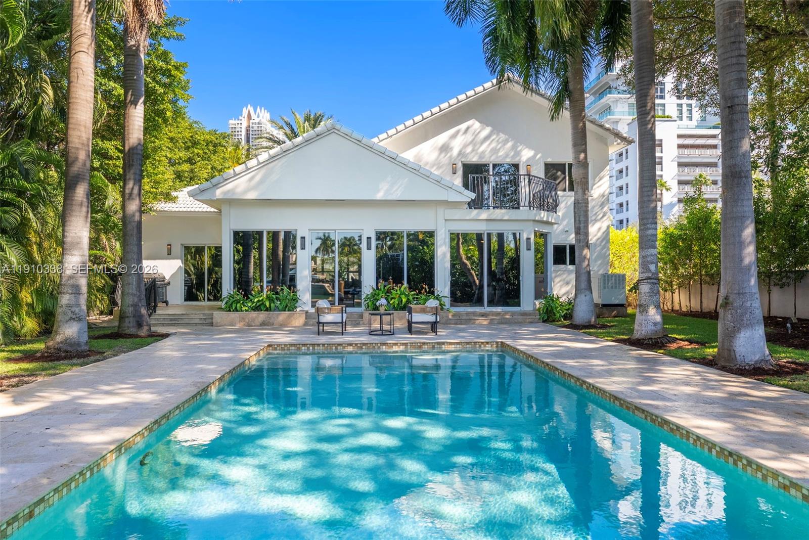 A white two-story house features a swimming pool and palm trees in the backyard — 6300 Allison Rd, Miami Beach FL 33141, MIAMI BEACH, FL