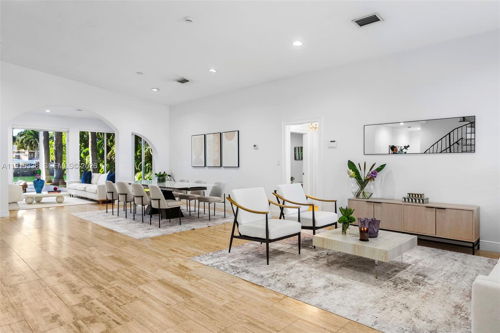A spacious, open-concept living and dining area features light wood-look tile floors and white walls — 6300 Allison Rd, Miami Beach FL 33141, MIAMI BEACH, FL