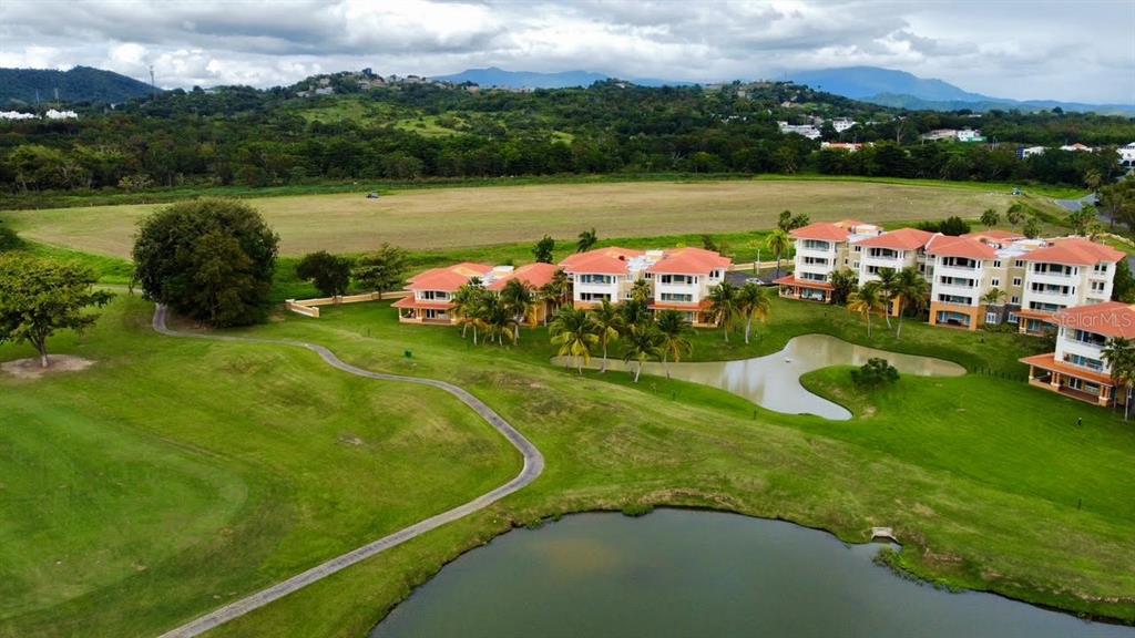 An aerial view shows multi-story apartment buildings situated next to a golf course and pond — ACADEMY DRIVE, HUMACAO, PR