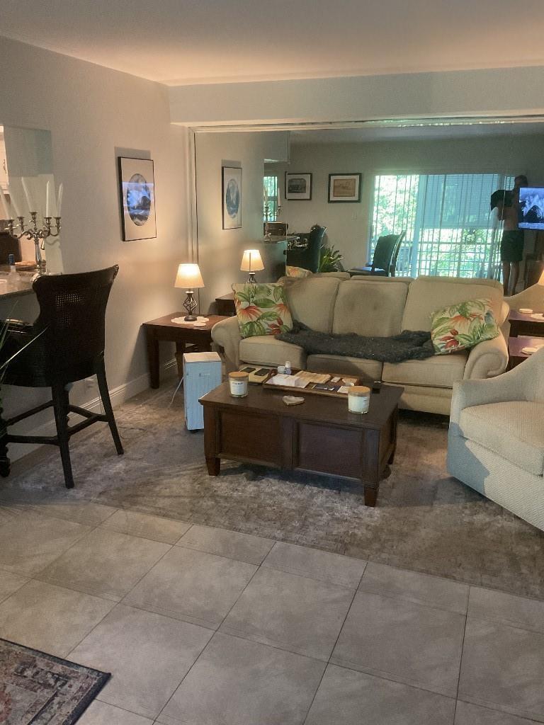 A living room features a beige sofa, a wooden coffee table, and a large mirrored wall — 100 SE 6th Avenue # 206, Pompano Beach FL 33060, POMPANO BEACH, FL