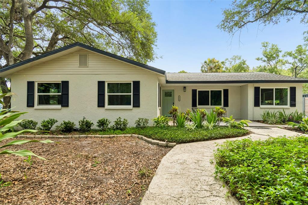 A single-story house with a light-colored exterior, dark shutters, and a stone walkway — 6214 15TH AVENUE S, TAMPA, FL