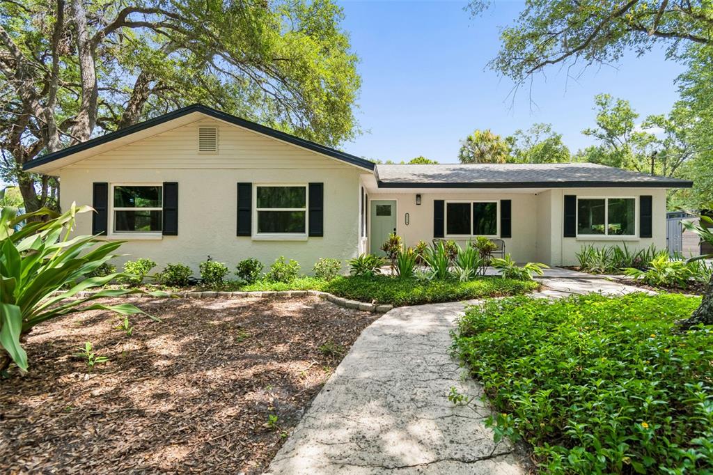 A single-story house with white stucco walls, black shutters, and a light green front door — 6214 15TH AVENUE S, TAMPA, FL