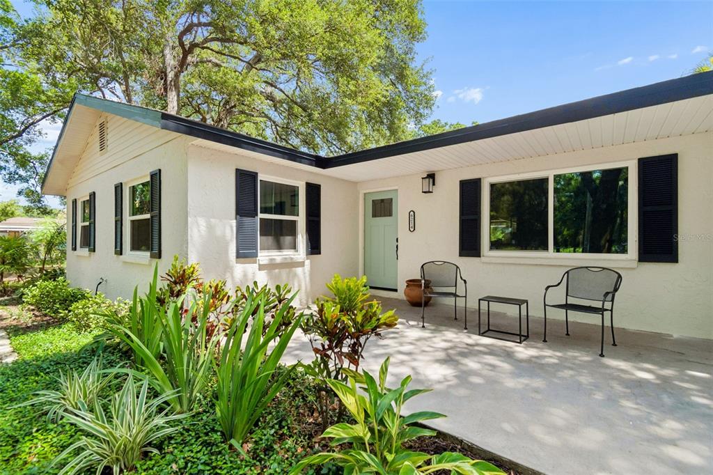 The exterior entryway features a light blue door, a window with dark shutters, and stucco walls — 6214 15TH AVENUE S, TAMPA, FL