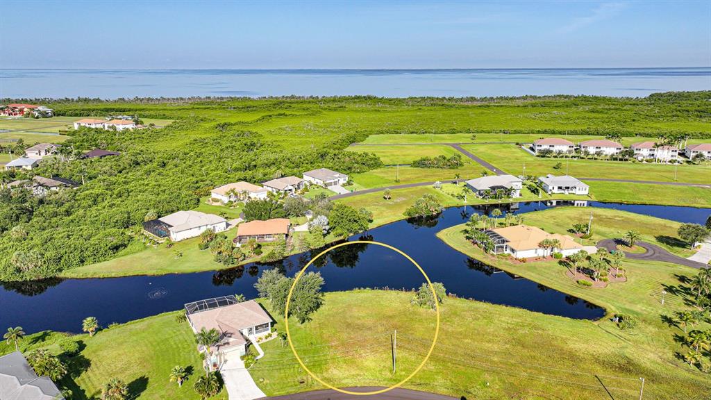 An aerial view shows a vacant waterfront residential lot highlighted by a yellow circle — 17357 YOSEMITE COURT, PUNTA GORDA, FL