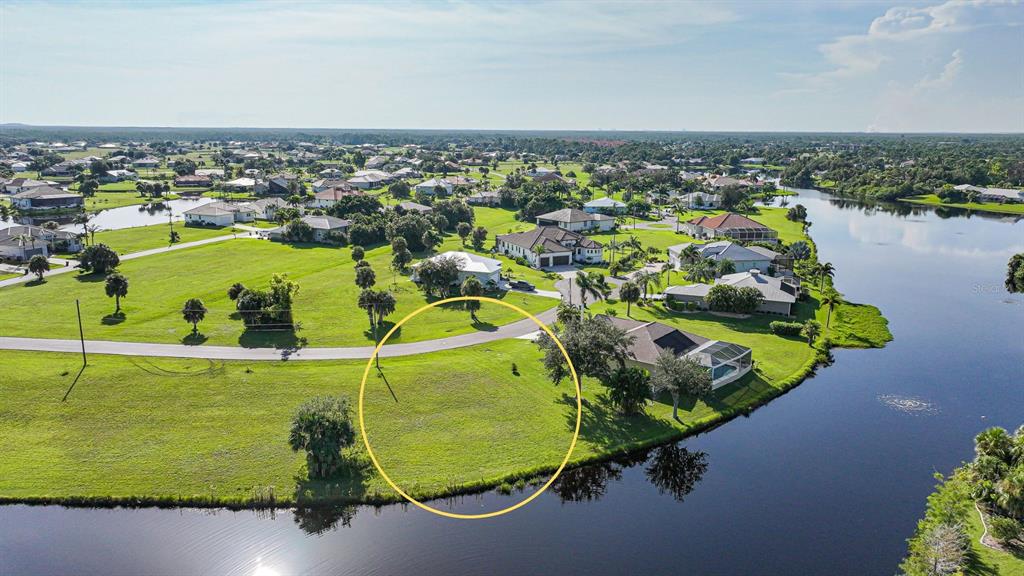 An aerial view of a vacant waterfront lot circled in yellow within a residential neighborhood — 17357 YOSEMITE COURT, PUNTA GORDA, FL