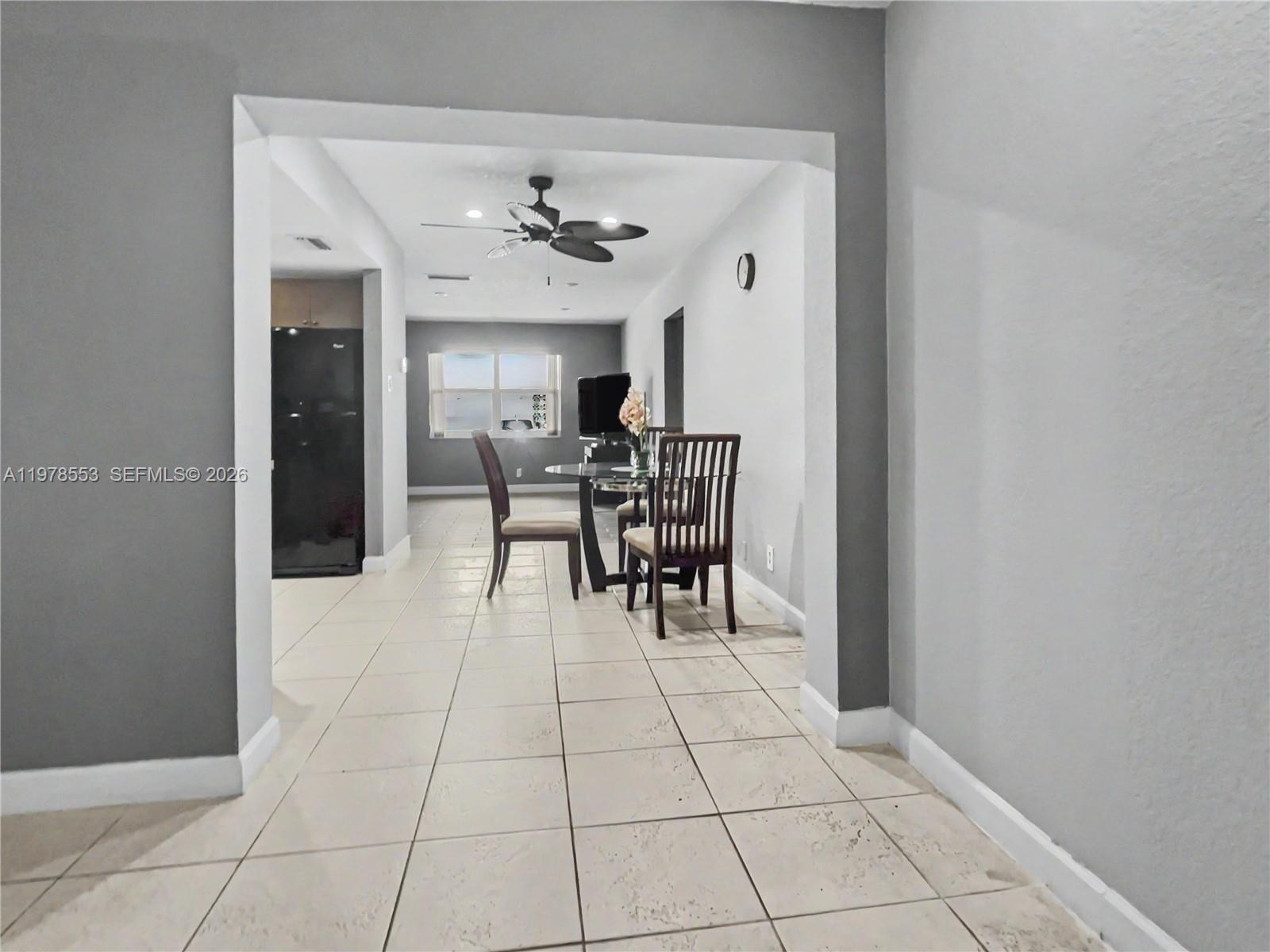 A dining area with a glass table and chairs sits between a kitchen and living room — 6960 NW 11th Ct, Margate FL 33063, MARGATE, FL