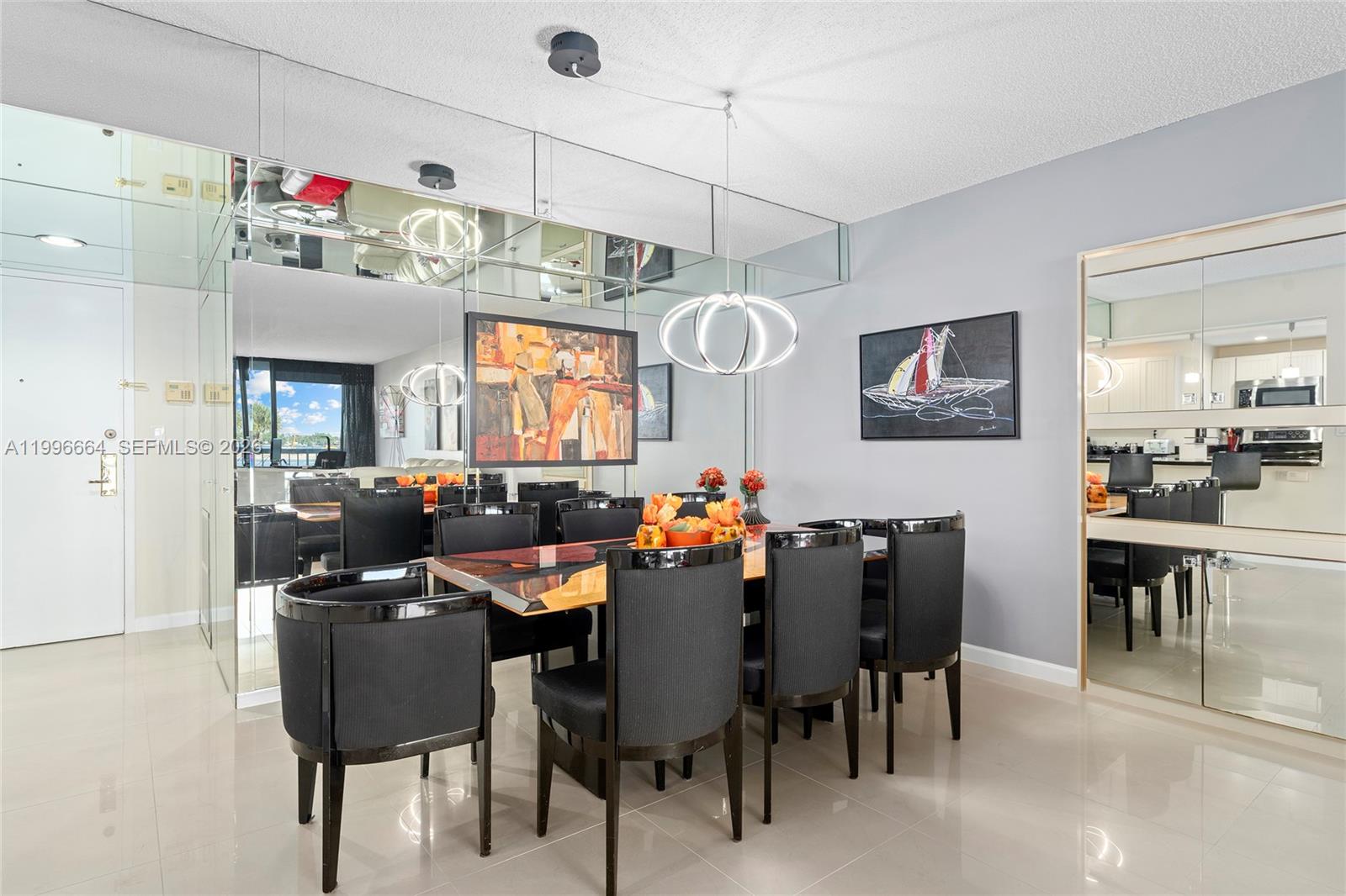 A dining room features a glass table, black chairs, mirrored walls, and modern pendant lighting — 3300 S Ocean Blvd # 207N, Palm Beach FL 33480, PALM BEACH, FL