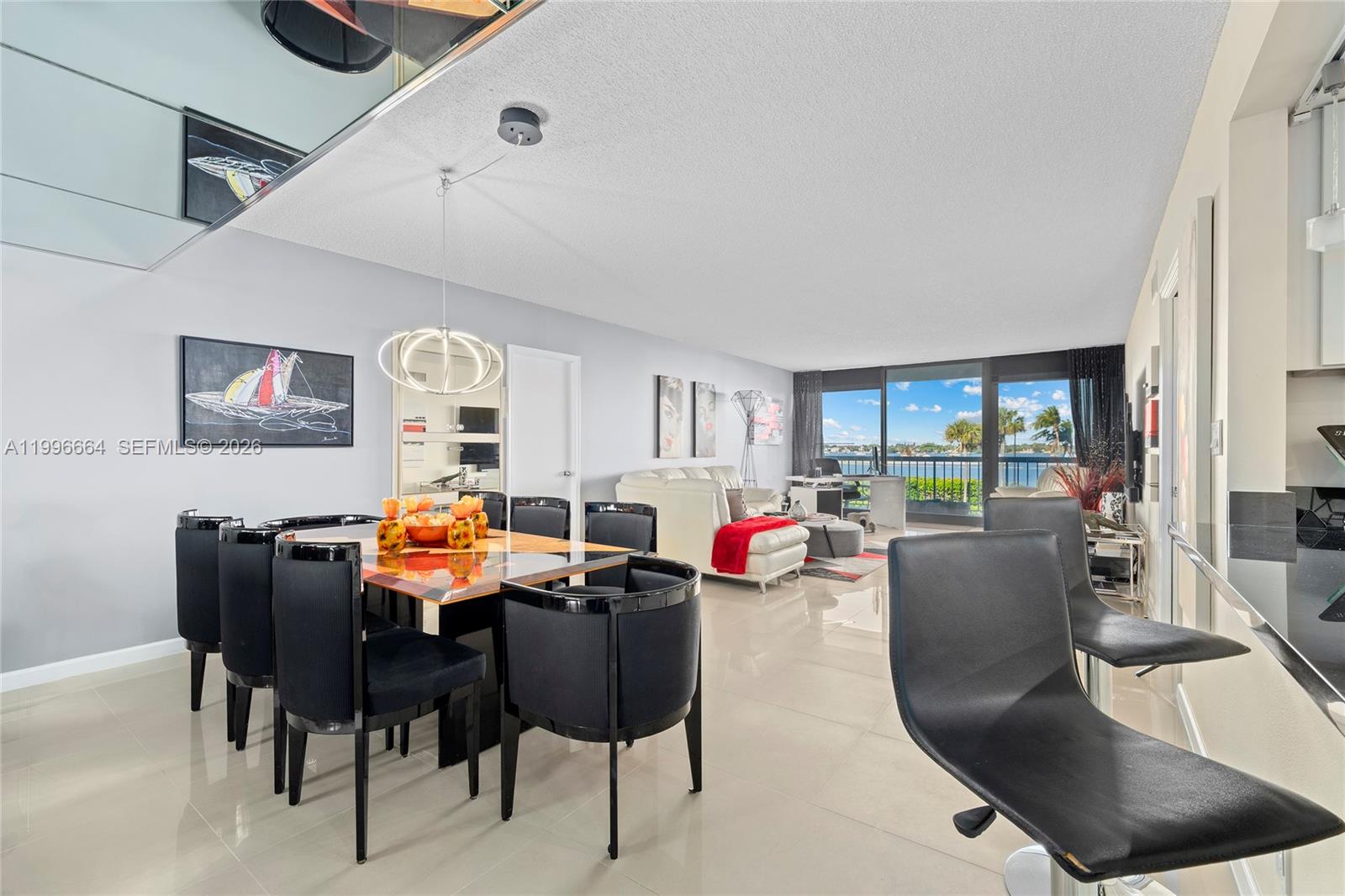 A dining area and living room with tile floors overlook a balcony and water view — 3300 S Ocean Blvd # 207N, Palm Beach FL 33480, PALM BEACH, FL