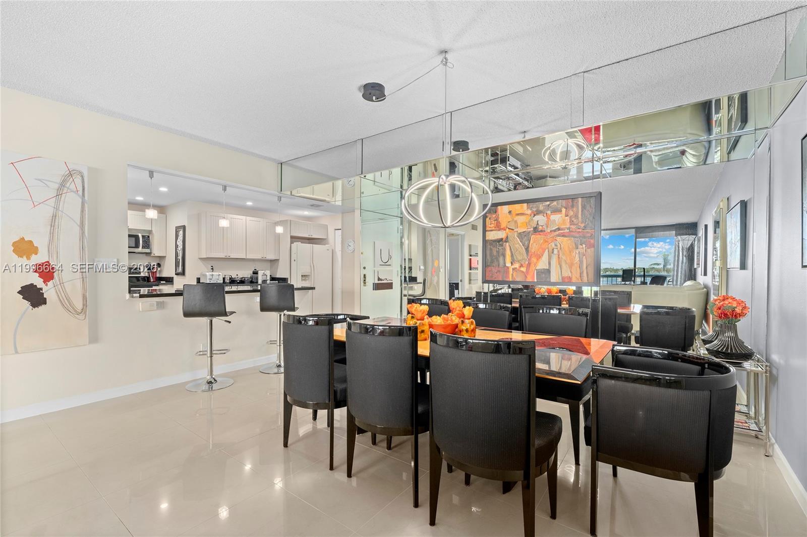A dining room with black chairs, a glass table, and mirrored walls near a kitchen — 3300 S Ocean Blvd # 207N, Palm Beach FL 33480, PALM BEACH, FL