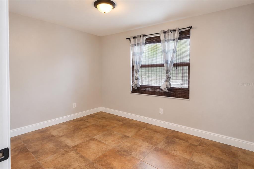 An empty room features light-colored walls, a tiled floor, and a window with curtains — 2232 SELKIRK STREET, VALRICO, FL