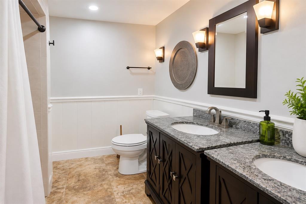 A bathroom features a double vanity with granite countertops, dark cabinetry, and white wainscoting — 2232 SELKIRK STREET, VALRICO, FL