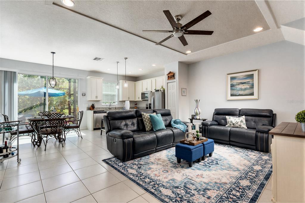 An open-concept living room and kitchen featuring tile floors, dark leather furniture, and a ceiling fan — 4848 CLIVEDEN LOOP, SANFORD, FL
