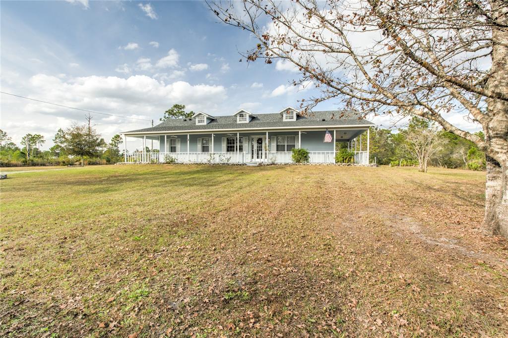 A light blue single-story house features a wrap-around porch and three dormer windows — 20351 SABAL STREET, ORLANDO, FL