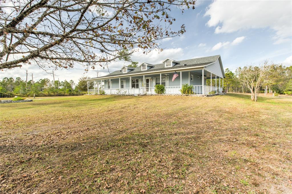A light blue house with a wraparound porch stands on a large, grassy lot — 20351 SABAL STREET, ORLANDO, FL