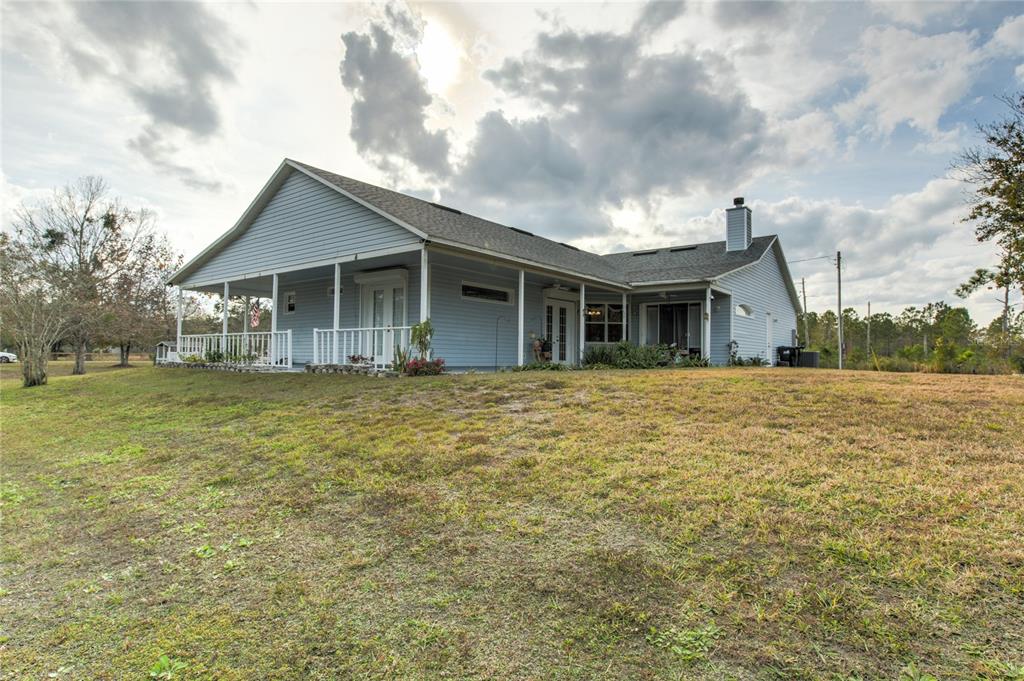 A light blue house with a wrap-around porch sits on a grassy lot — 20351 SABAL STREET, ORLANDO, FL