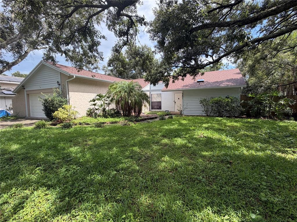 A single-story house with a garage, light-colored siding, and a large front yard with trees — 4601 FARMHOUSE DRIVE, TAMPA, FL