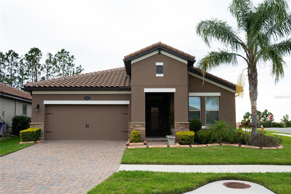A single-story house with a brown stucco exterior, tile roof, and a paved driveway — 4004 PRIMA LAGO CIRCLE, LAKELAND, FL