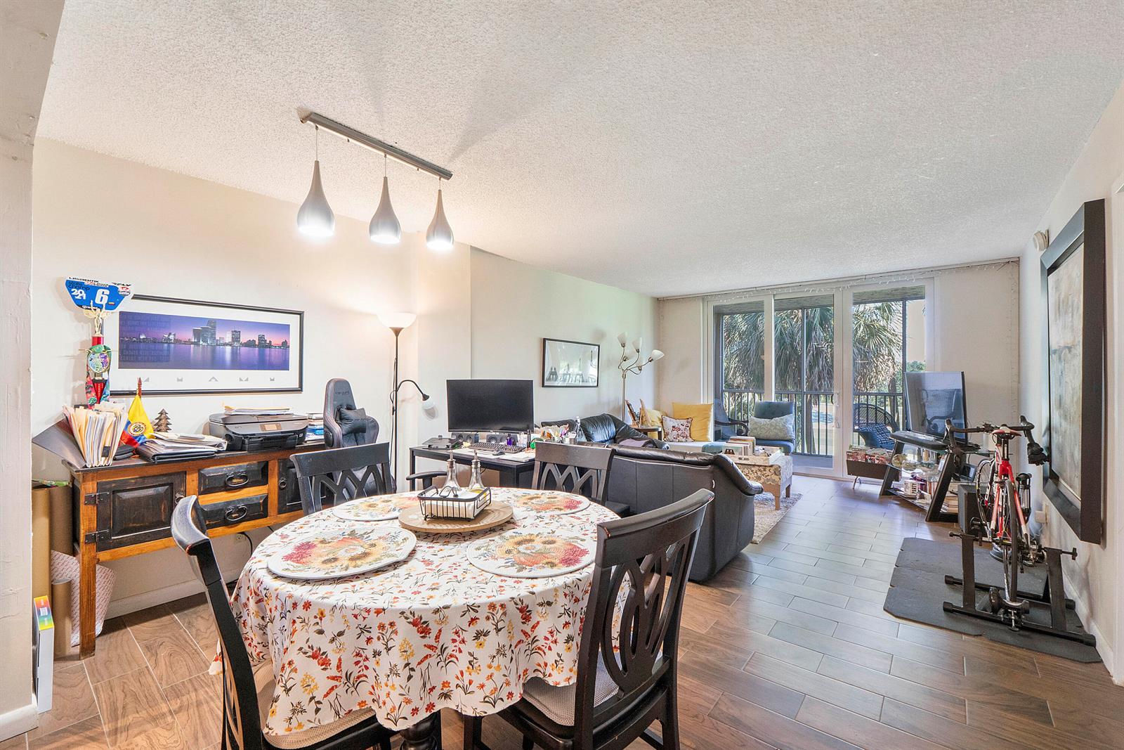 An open-concept living and dining area features tile flooring, a round floral table, and a balcony — 250 Jacaranda Drive # 308, Plantation FL 33324, PLANTATION, FL