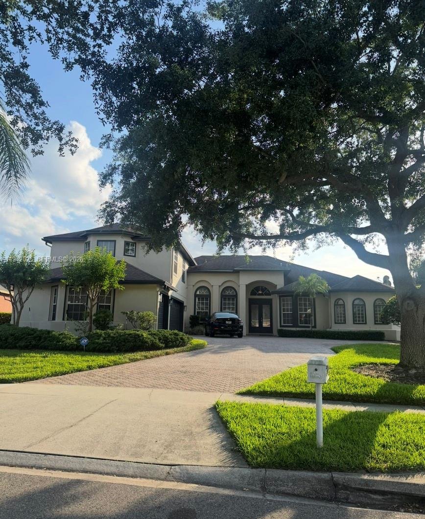 A two-story house with a paved driveway, arched windows, and a large tree in front — 10020 Honey Tree Ct, Orlando FL 32836, ORLANDO, FL