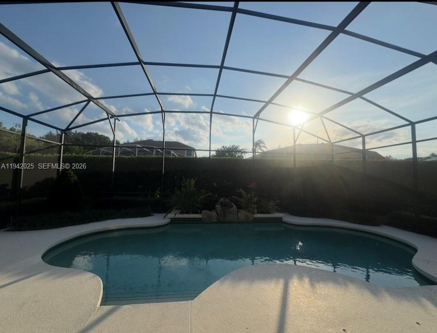 A swimming pool is enclosed by a screened lanai with a rock water feature — 10020 Honey Tree Ct, Orlando FL 32836, ORLANDO, FL