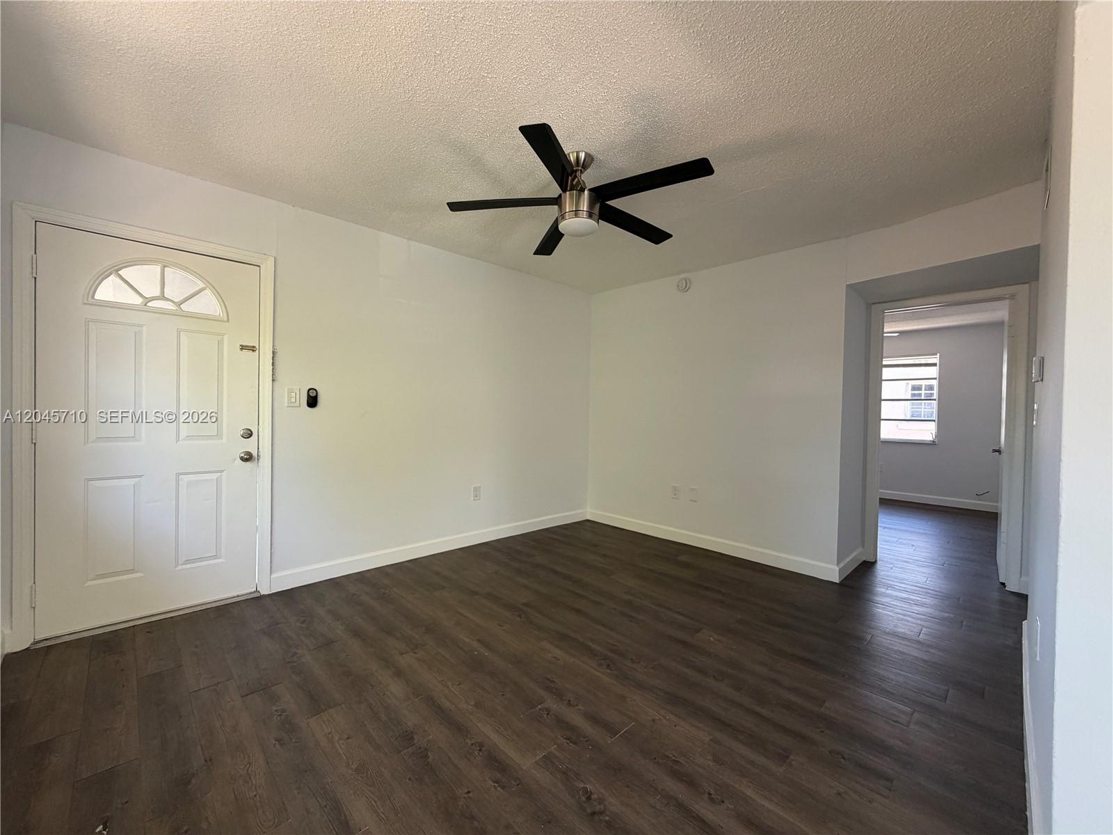 An empty room features white walls, dark wood-look flooring, and a ceiling fan — 5954 NE 4th Ct # 6, Miami FL 33137, MIAMI, FL