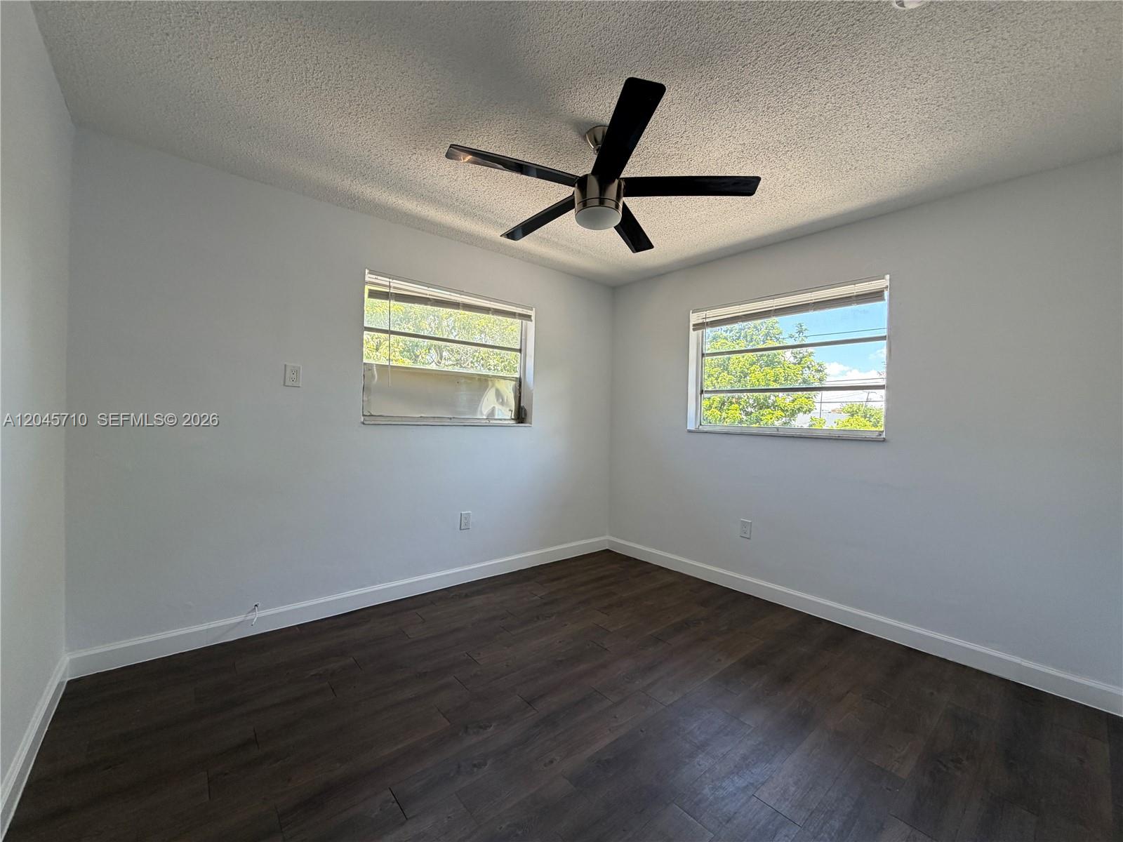 An empty bedroom features white walls, dark wood-look flooring, and a ceiling fan — 5954 NE 4th Ct # 6, Miami FL 33137, MIAMI, FL