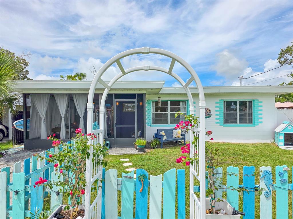A single-story house with a white arched trellis, turquoise picket fence, and screened-in porch — 926 FERNALD STREET, EDGEWATER, FL