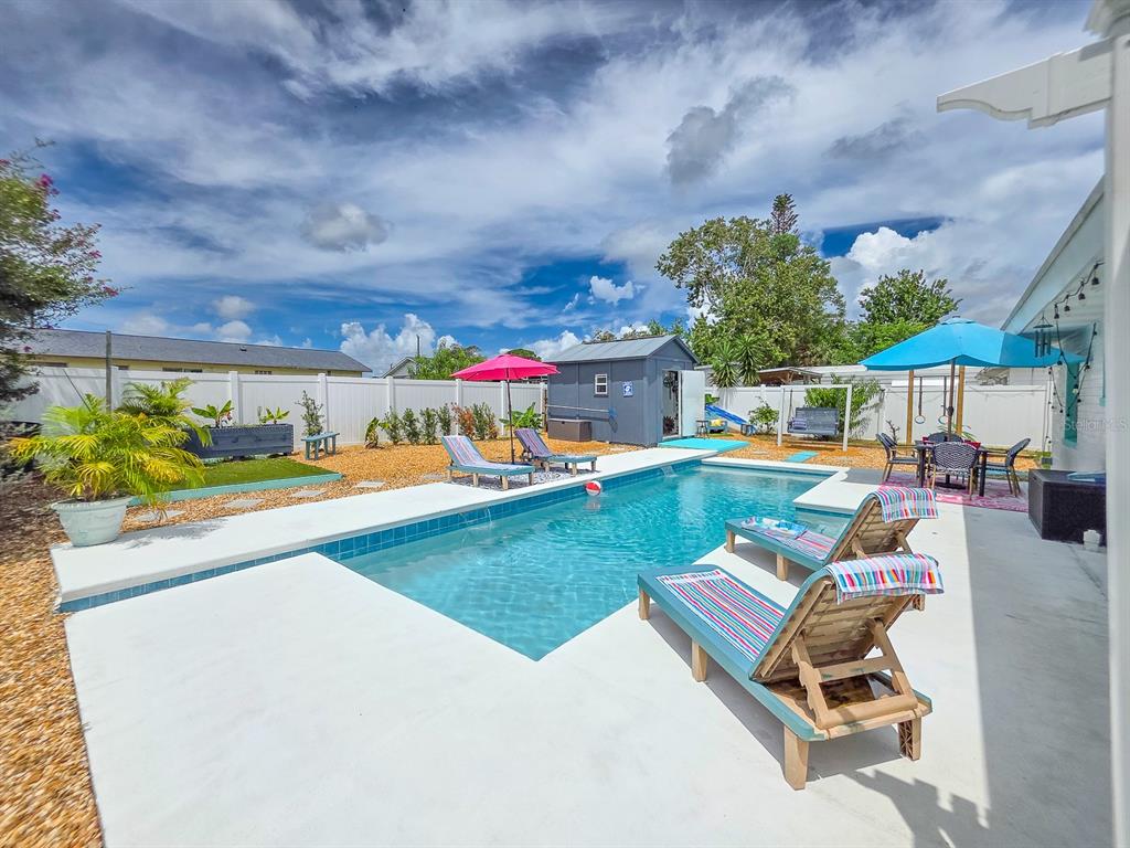 A backyard features a rectangular swimming pool, lounge chairs, a shed, and a white fence — 926 FERNALD STREET, EDGEWATER, FL
