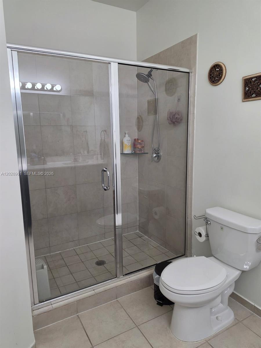 A bathroom features a tiled walk-in shower with a glass door and a white toilet — HIALEAH, FL