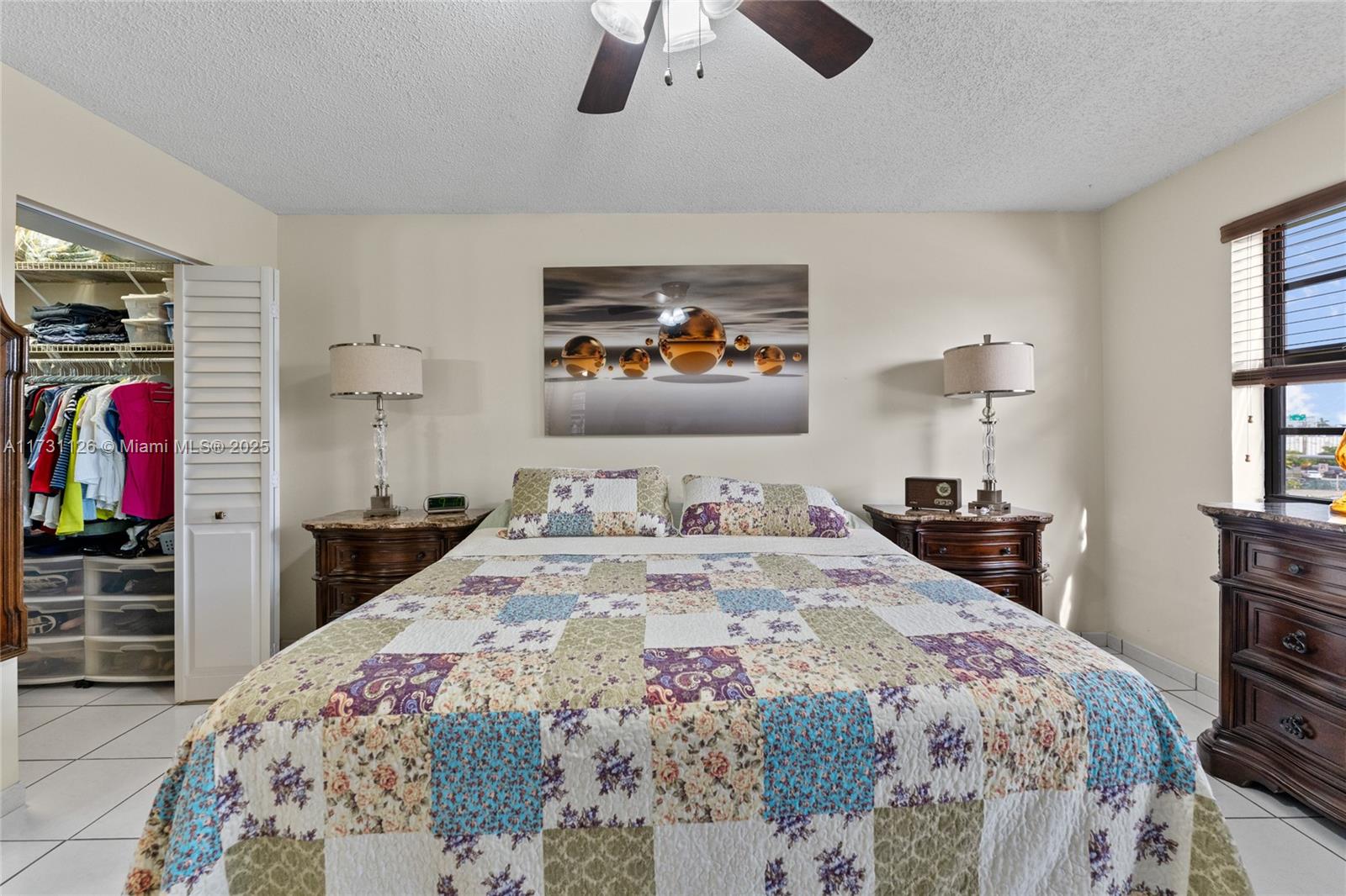 A bedroom features a patchwork quilt bed, two nightstands with lamps, and a walk-in closet — 605 NW 72nd Ave # 406, Miami FL 33126, MIAMI, FL