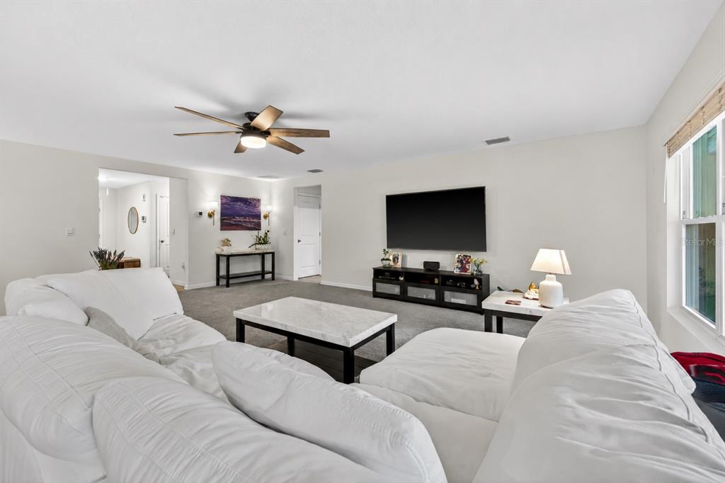 A living room features a white sectional sofa, a marble coffee table, and a wall-mounted television — 5442 DIANTHA WAY, BROOKSVILLE, FL