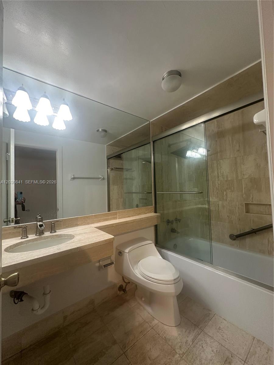 A bathroom features a vanity with a stone countertop, a toilet, and a tiled shower — 700 Biltmore Way # 408, Coral Gables FL 33134, CORAL GABLES, FL