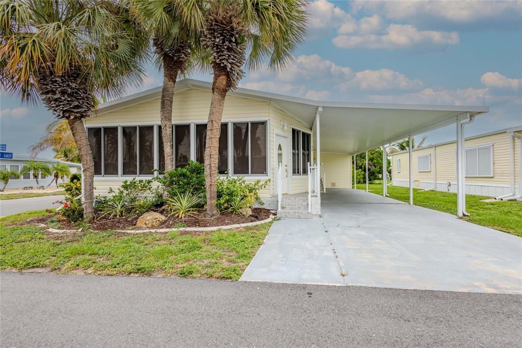 A yellow mobile home features a screened-in front porch, a carport, and two palm trees — 2100 KINGS HIGHWAY UNIT 529, PORT CHARLOTTE, FL