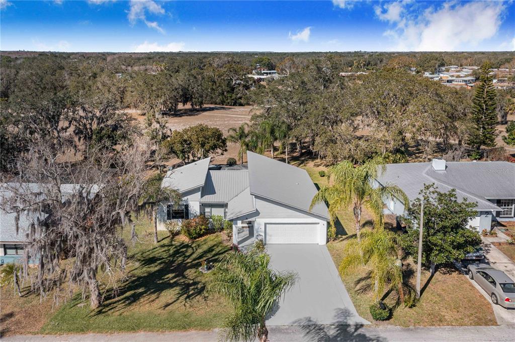 An aerial view shows a single-story house with a metal roof and a concrete driveway — 3 MAPLE RUN, HAINES CITY, FL
