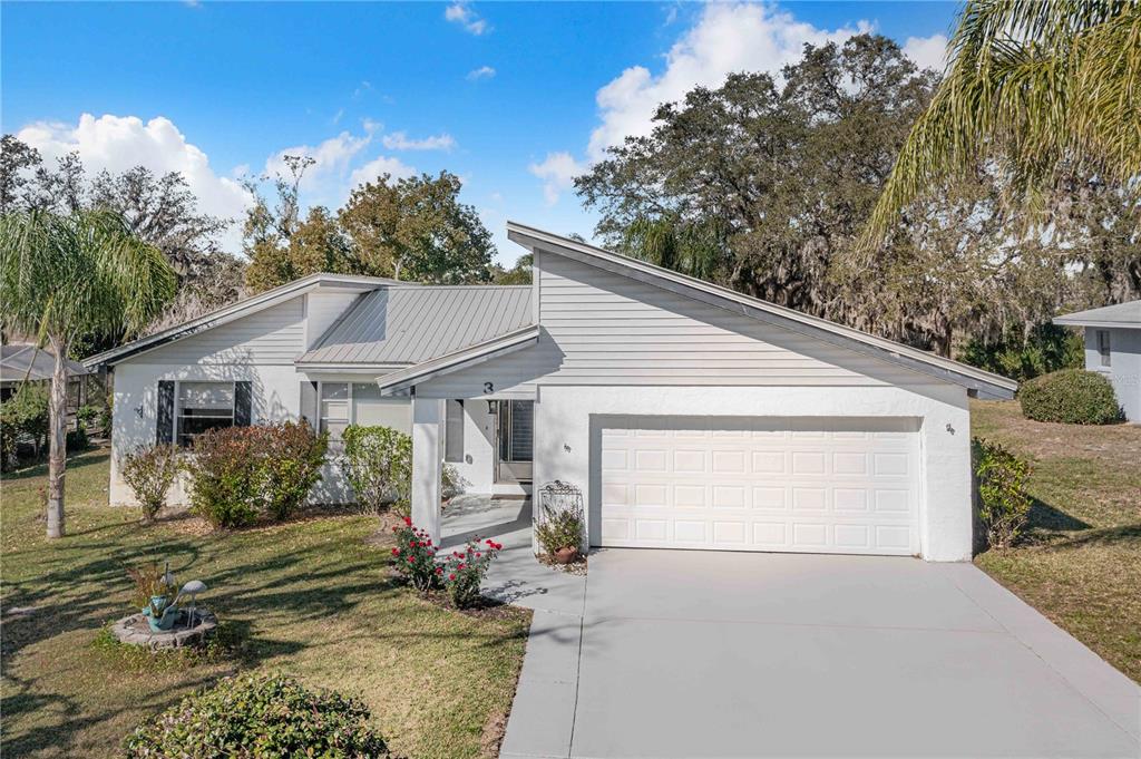 A single-story house with a white exterior, metal roof, and a two-car garage — 3 MAPLE RUN, HAINES CITY, FL