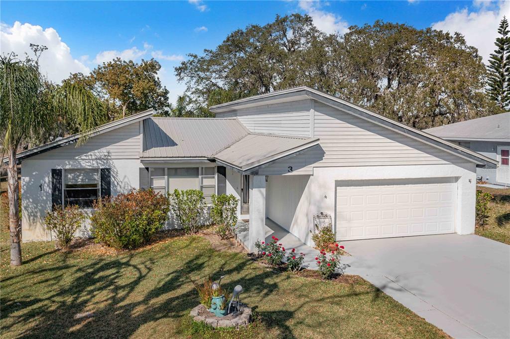 A single-story house with a white exterior, metal roof, and an attached two-car garage — 3 MAPLE RUN, HAINES CITY, FL