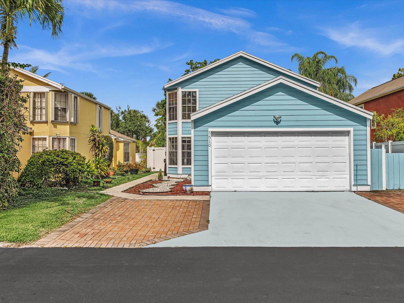 A blue two-story house with a white garage door and a brick-paved driveway — 5610 Dewberry Way, West Palm Beach FL 33415, WEST PALM BEACH, FL