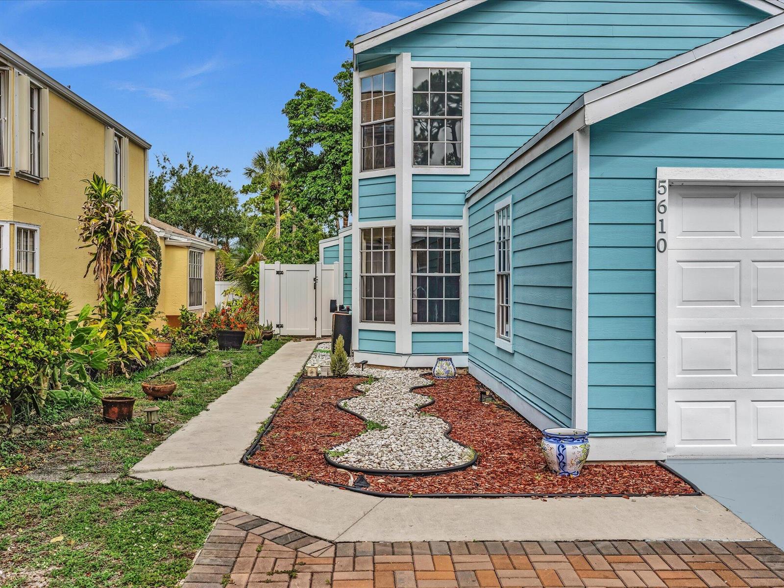 A blue house with a white garage door and a landscaped front yard with gravel — 5610 Dewberry Way, West Palm Beach FL 33415, WEST PALM BEACH, FL