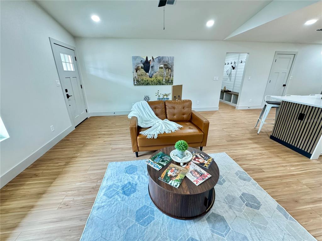 A living room features a brown leather loveseat, a round coffee table, and light wood flooring — 823 NW 13TH AVENUE, OCALA, FL